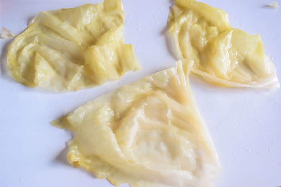Sour cabbage leaves on white cutting board.