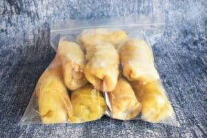 Cabbage rolls in a zip-top bag, blue background.