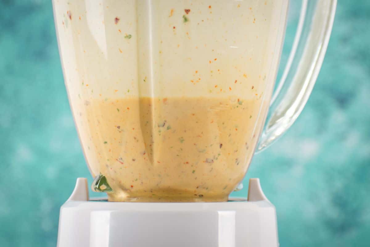 Chipotle sauce in a blender on blue background.