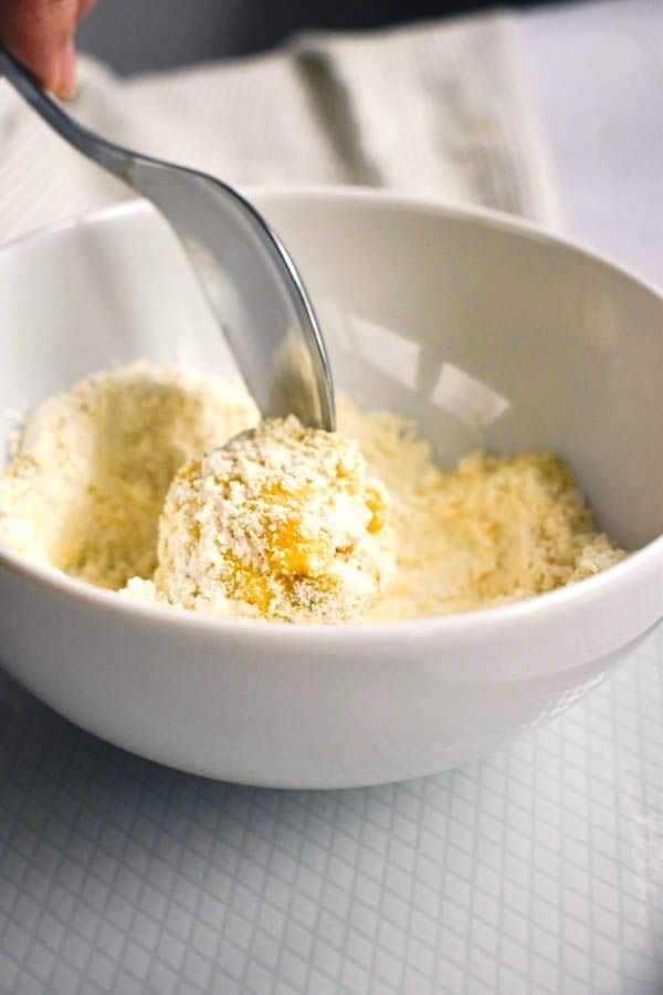 A bowl of flour covering a raw corn nugget.