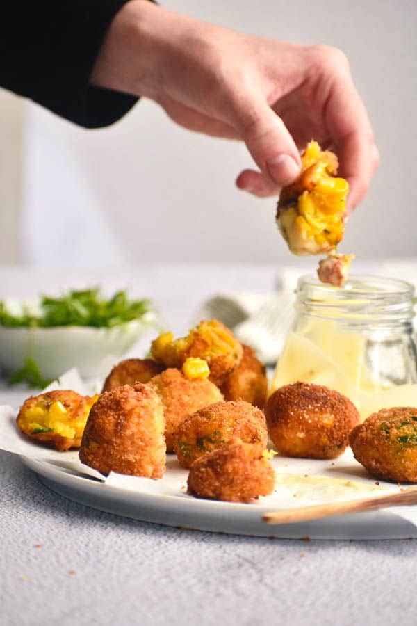 A plate of corn nuggets with dipping sauce.