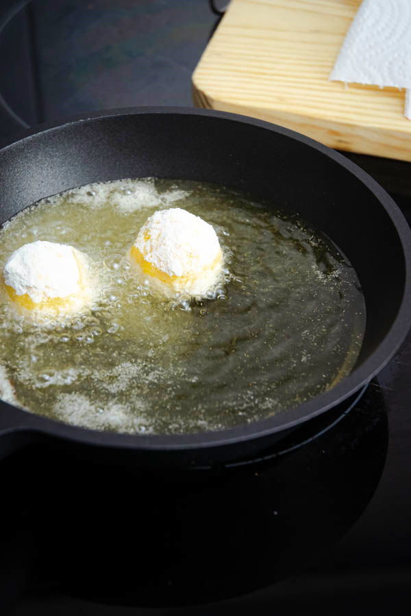 Fried corn nuggets in a pan with hot oil.