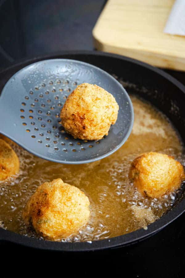 Fried corn nuggets in a pan with hot oil.