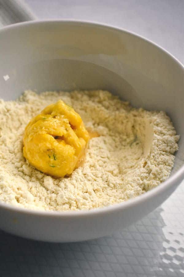 A raw corn nugget in a bowl of flour.
