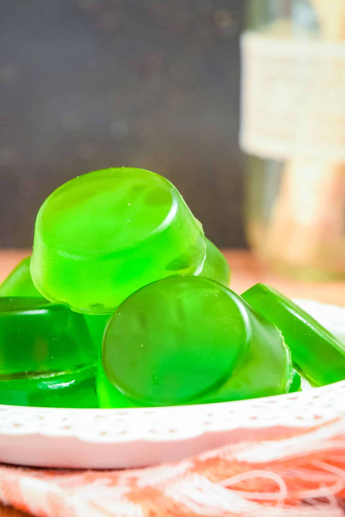 Green gummies on white plate.