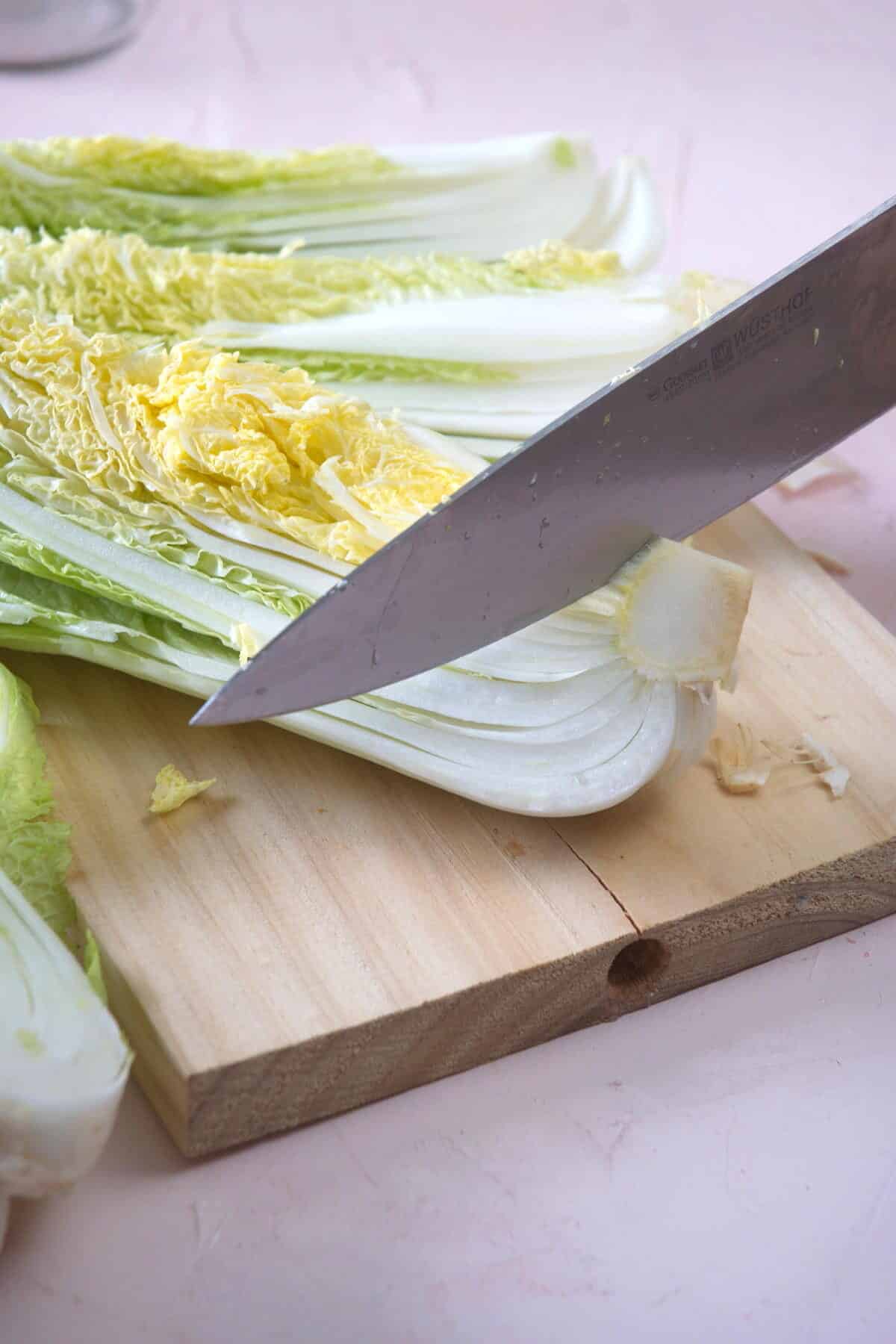 Napa cabbage and a chef's knife on a cutting board.