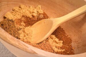 Pumpkin pie spice mix in wooden bowl with wooden spoon.
