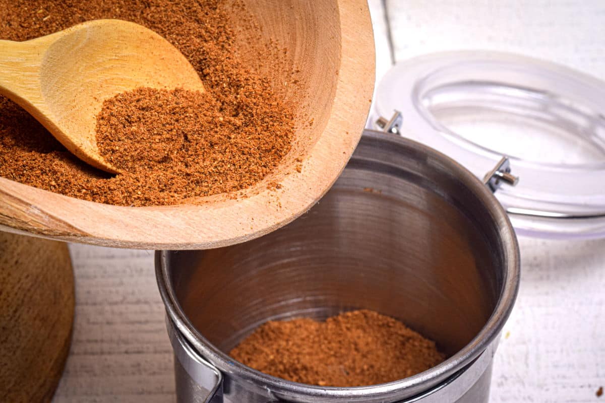 Pumpkin pie spice mix in wooden bowl with wooden spoon.