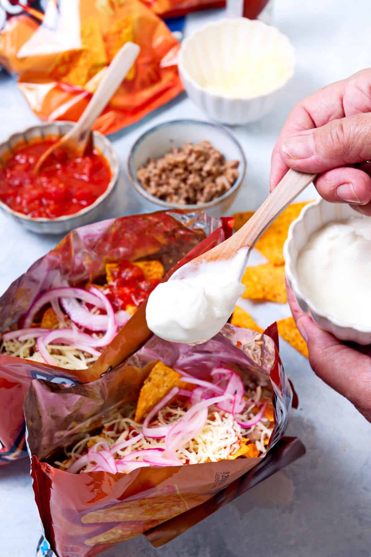 Open Dorito bags with taco filling and sour cream.