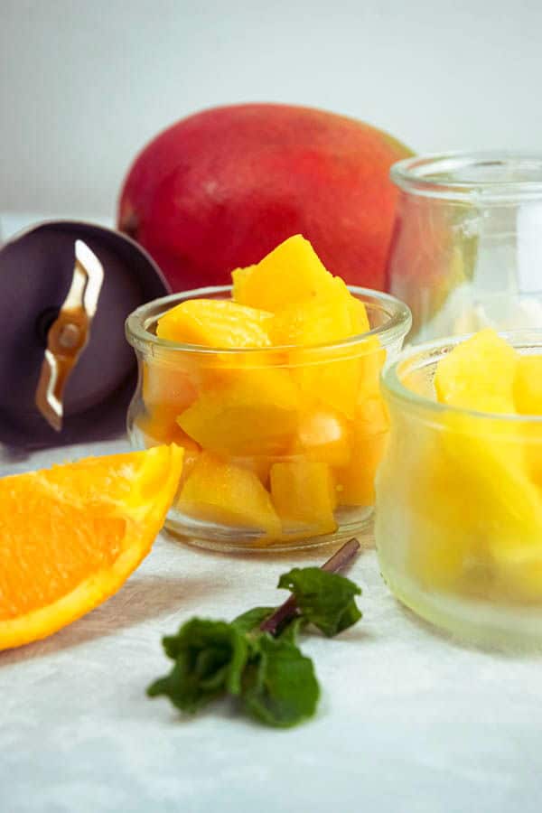 Mango pineapple smoothie ingredients on white background.