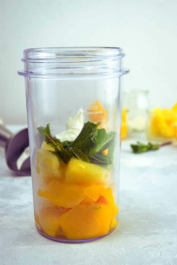 Mango pineapple smoothie ingredients in a jar.