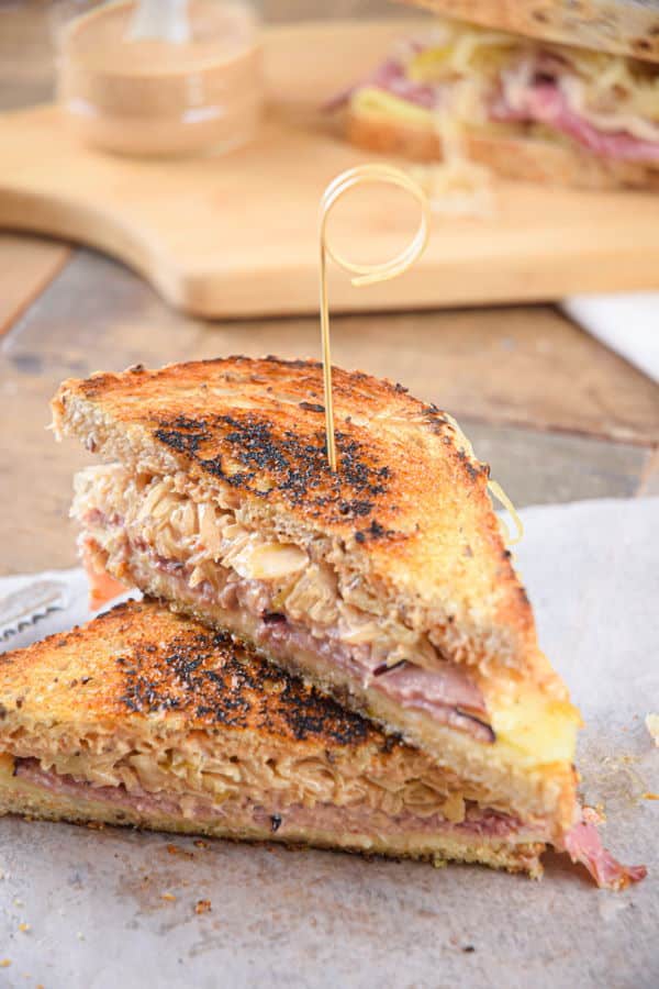Reuben sandwich halves stacked on top of each other on wooden background.