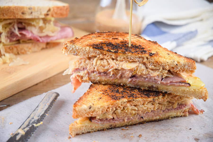 Reuben sandwich halves stacked on top of each other on parchment.