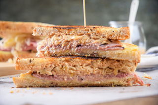 Reuben sandwich halves stacked on top of each other on parchment.