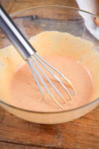 A bowl of Russian dressing with a whisk.