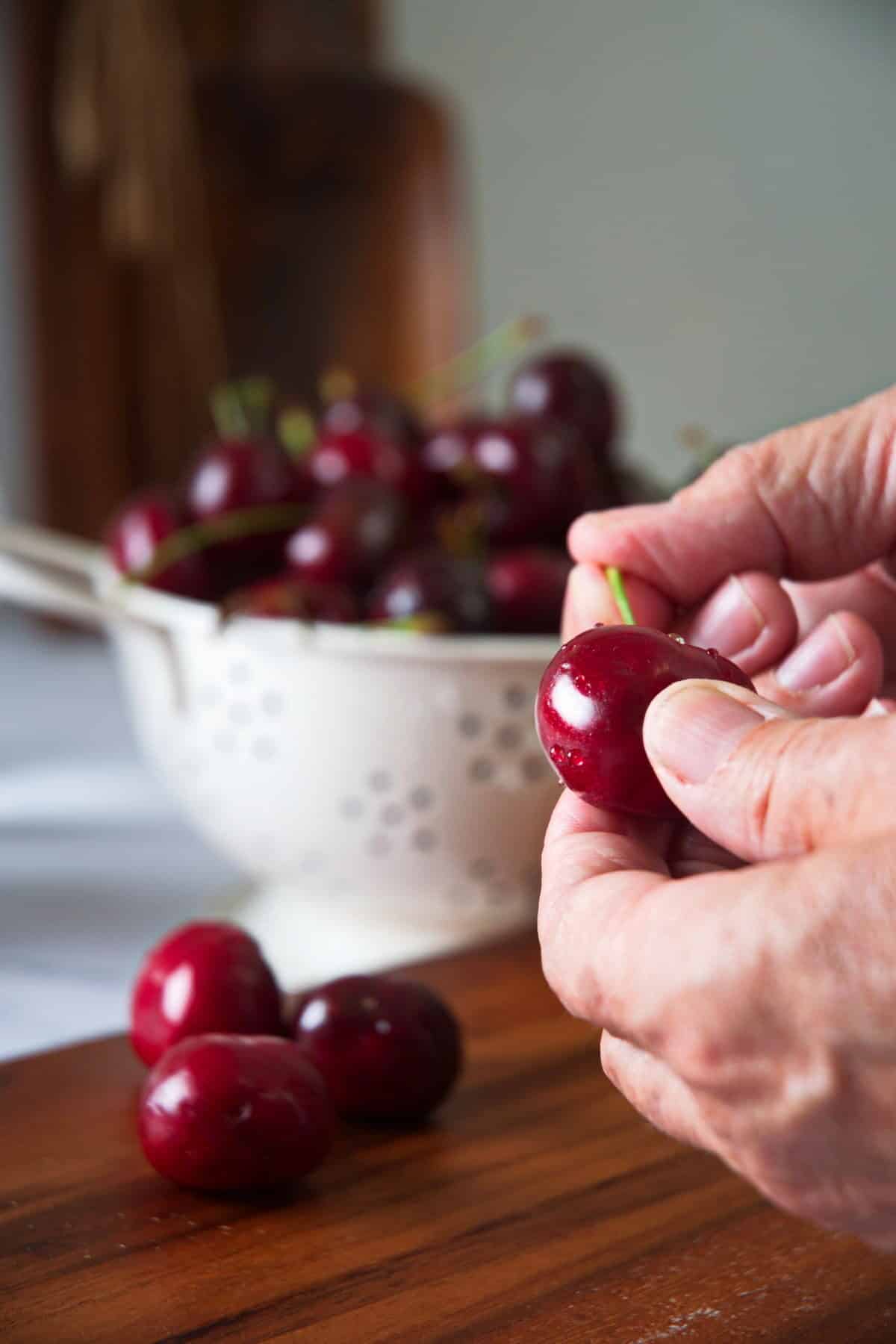 A woman's hand holding a cherry.