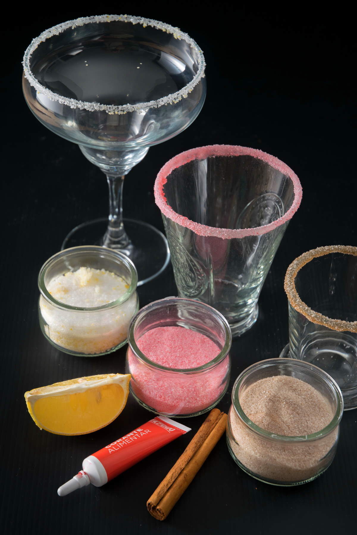 Sugar rim flavors in 3 jars with glasses in the background.