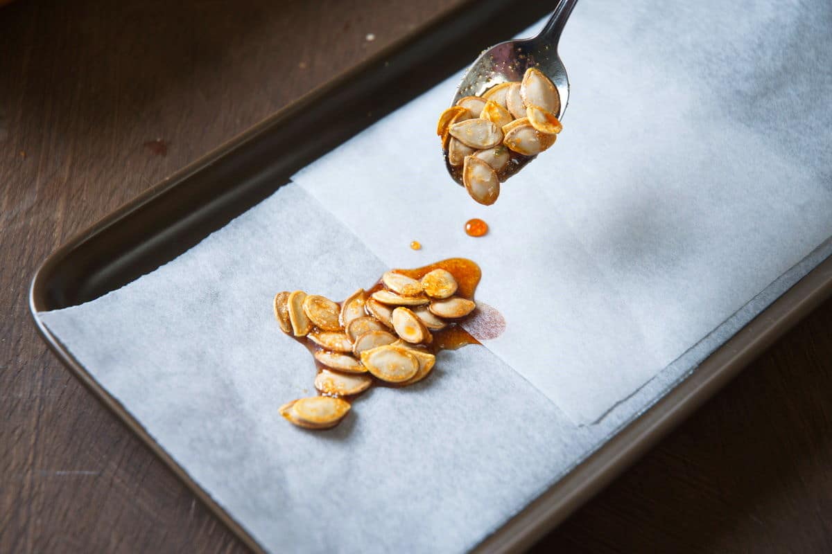 Butternut squash seeds on a parchment paper lined sheet pan.