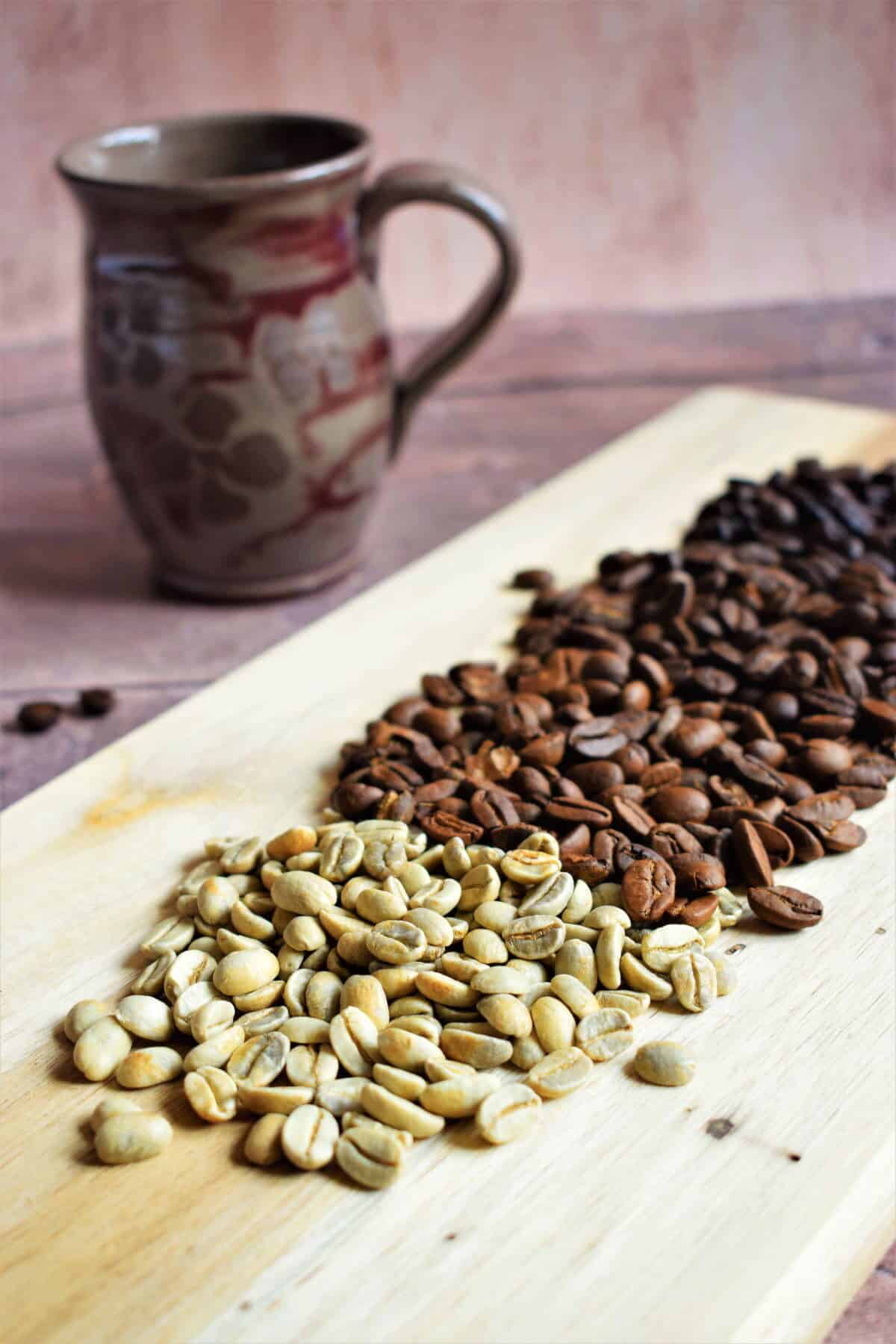 Green and brown coffee beans on wooden serving board.