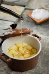 Peeled garlic cloves in a small baking dish with olive oil.