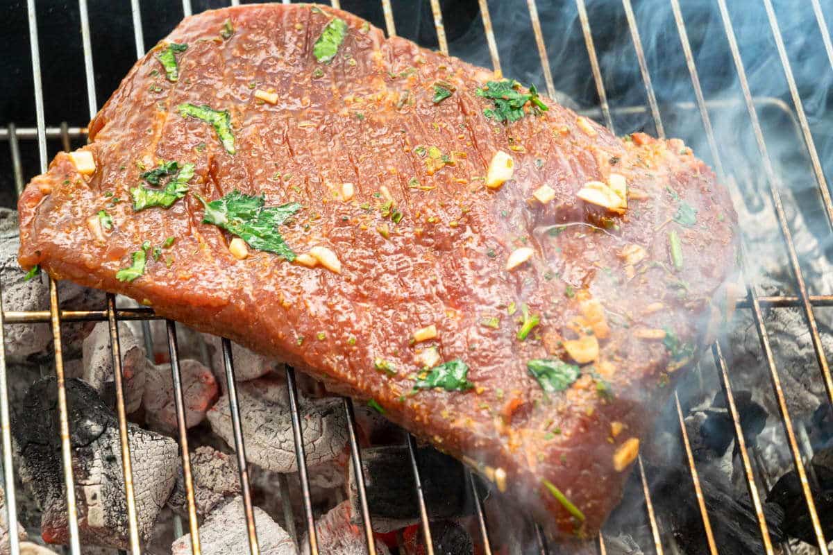 Marinated flank steak on grill.