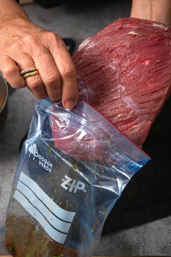 Raw flank steak in zip top bag.