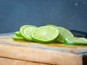 Lime slices on wooden cutting board.