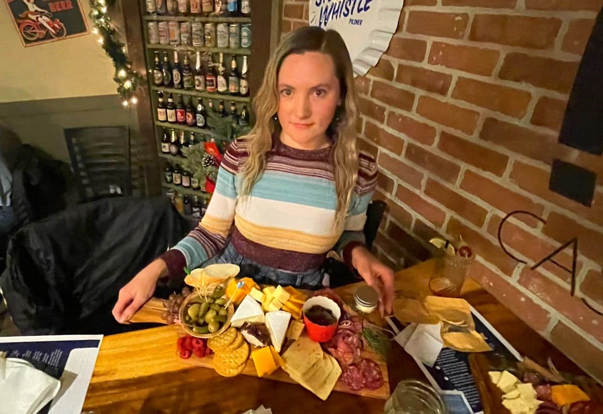 Joss holding a charcuterie board at restaurant table.