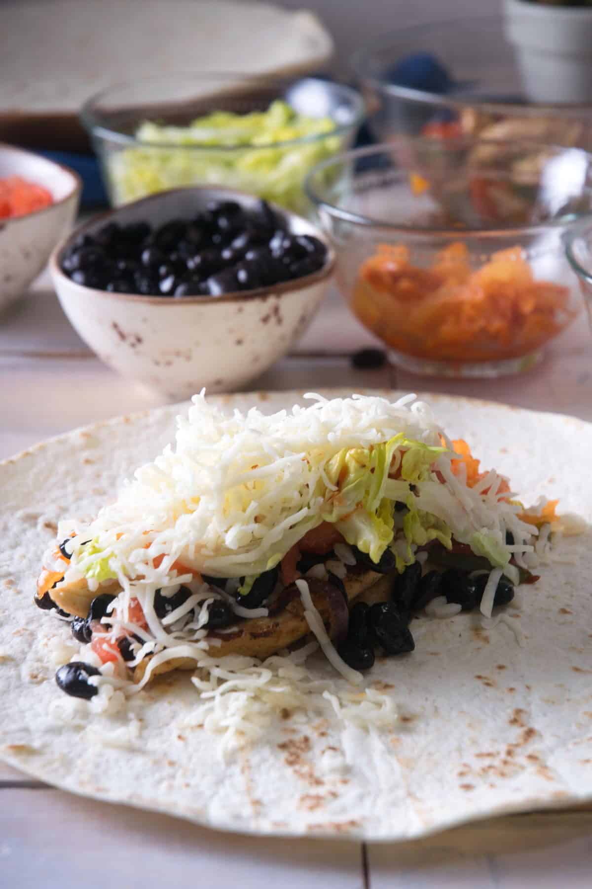 Kimchi burrito filling on tortilla, prepped ingredients in the background.