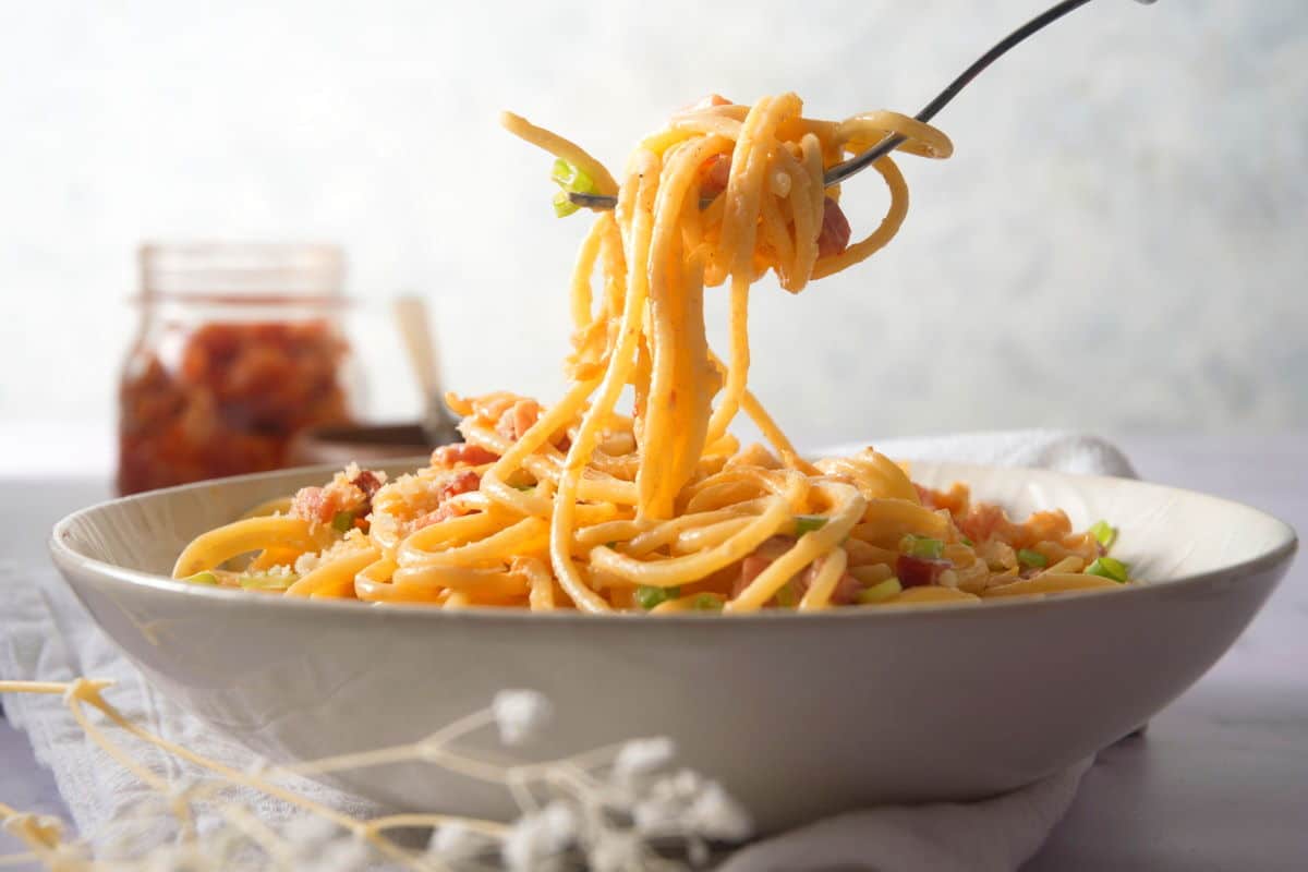 Kimchi carbonara around a fork in a white bowl.