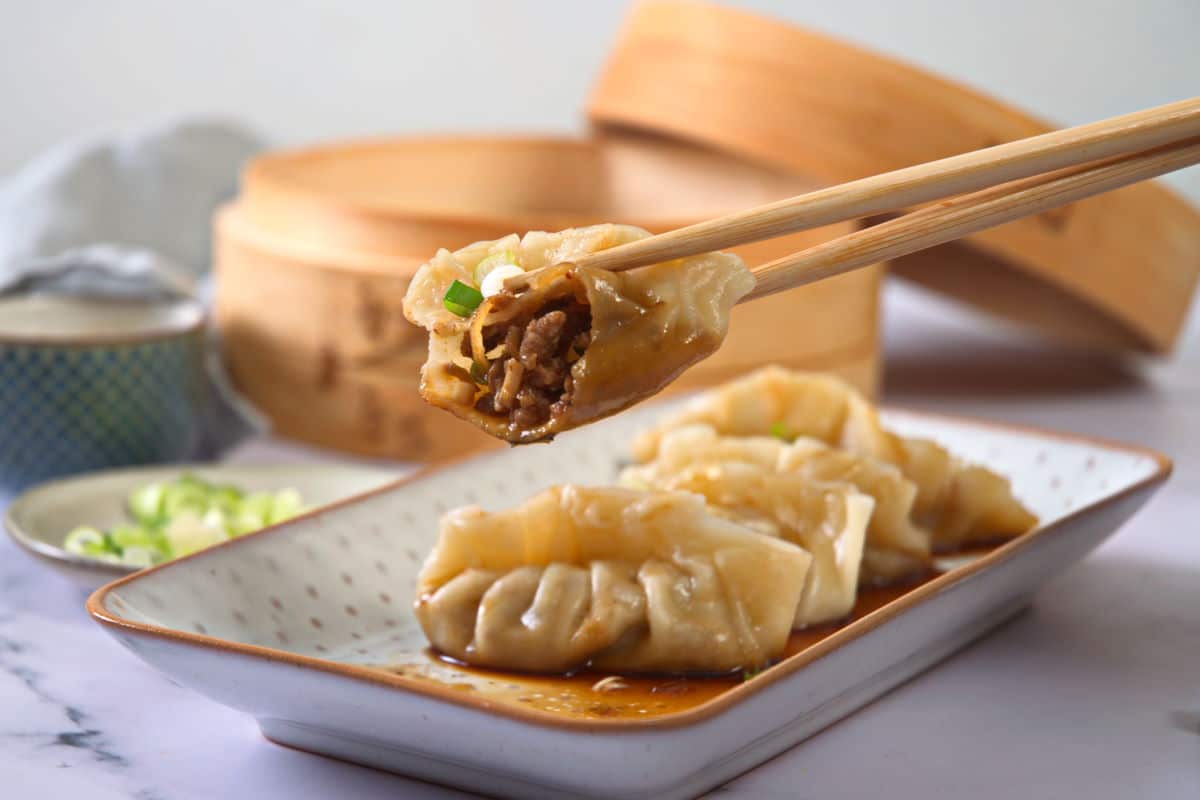 An open dumpling held in chopsticks.