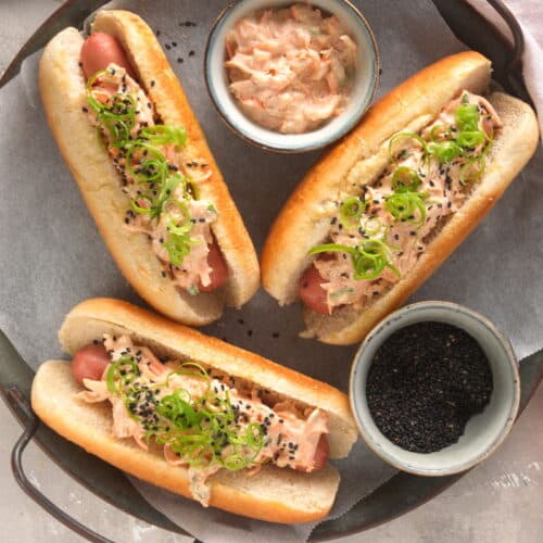 Top view of hot dogs with kimchi topping, black sesame sides on the side.