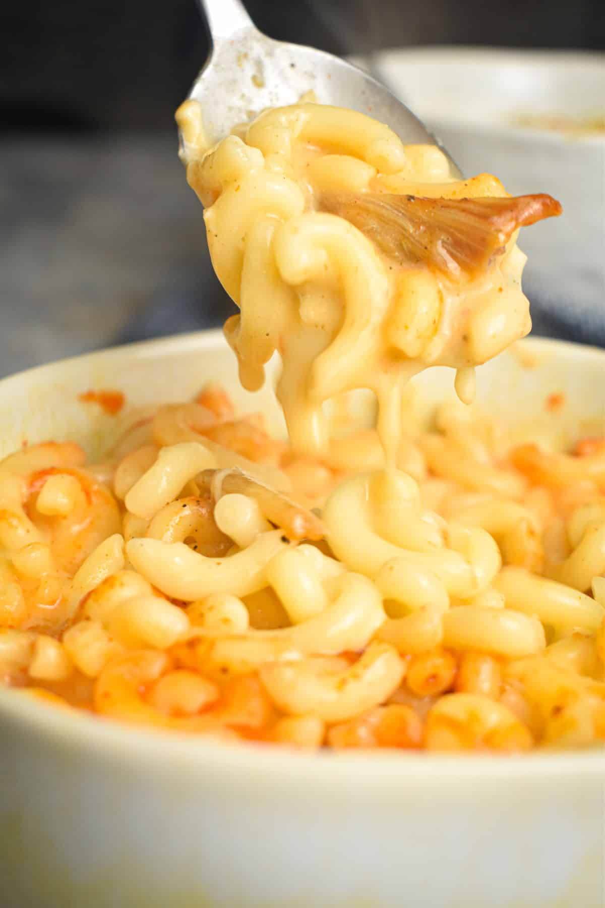 Kimchi mac and cheese in a white bowl and on a spoon.