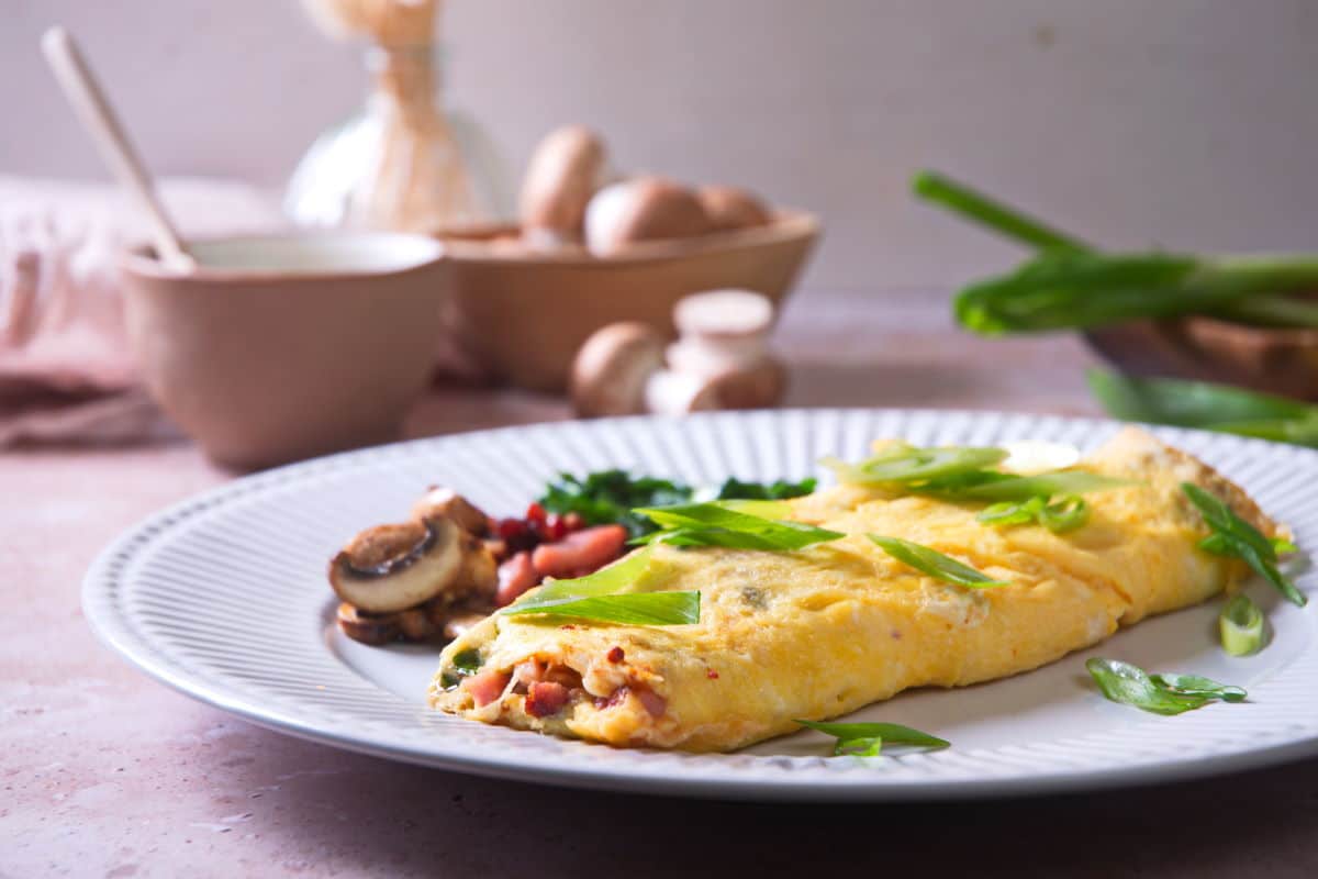 Kimchi omelette on white plate with sliced scallions.