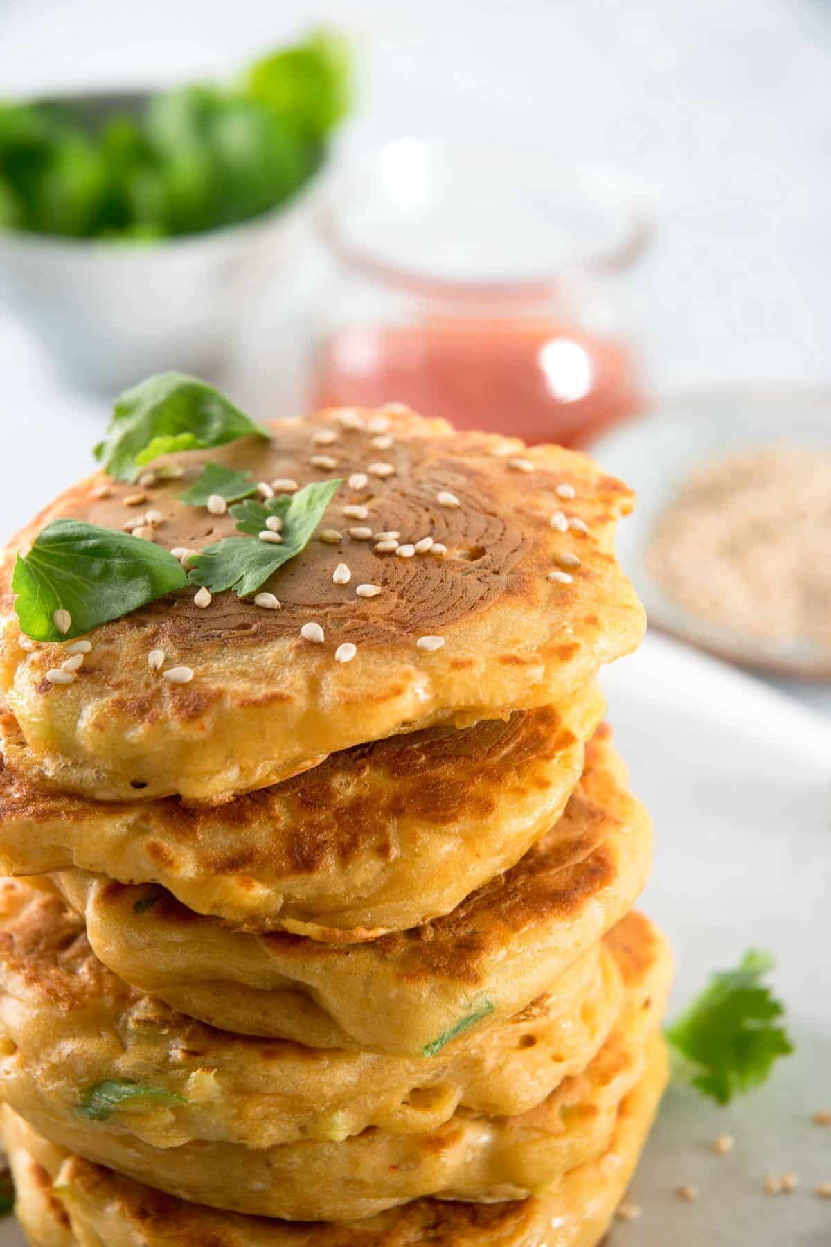 Kimchi pancakes stacked with sweet and sour sauce and sesame seeds.