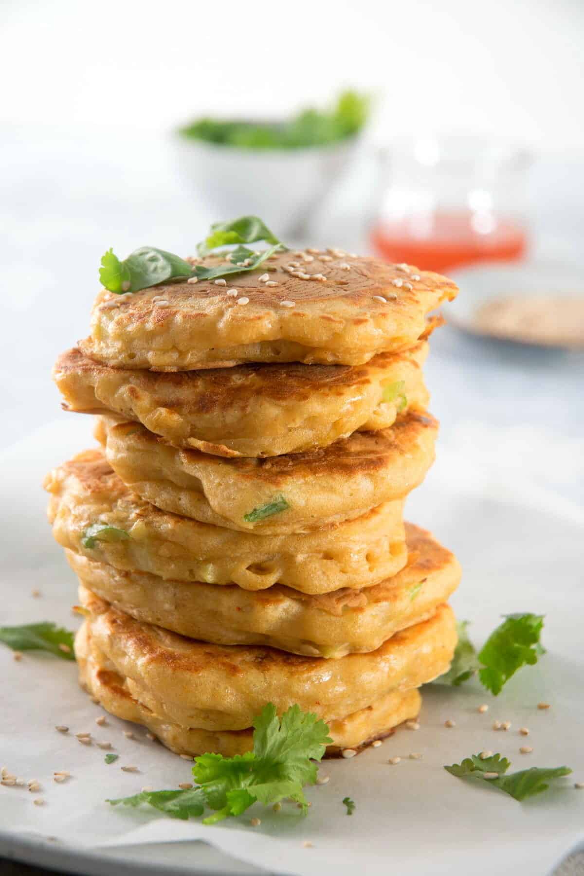 Kimchi pancakes stacked with sweet and sour sauce and sesame seeds.