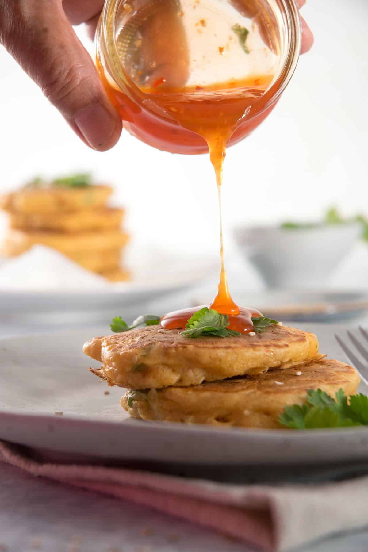 Kimchi pancakes stacked with sweet and sour sauce and sesame seeds.