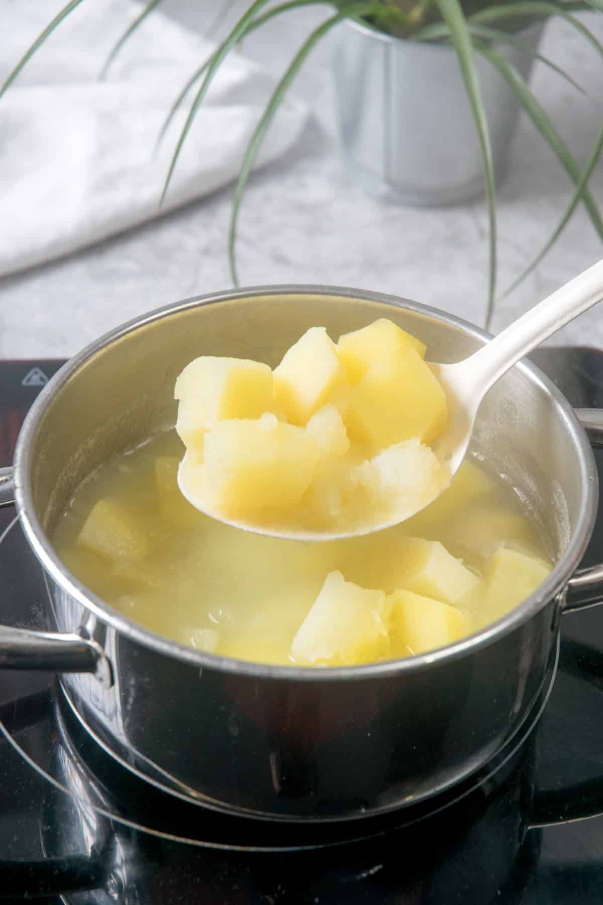 Cooked, cubed potatoes in a pot.