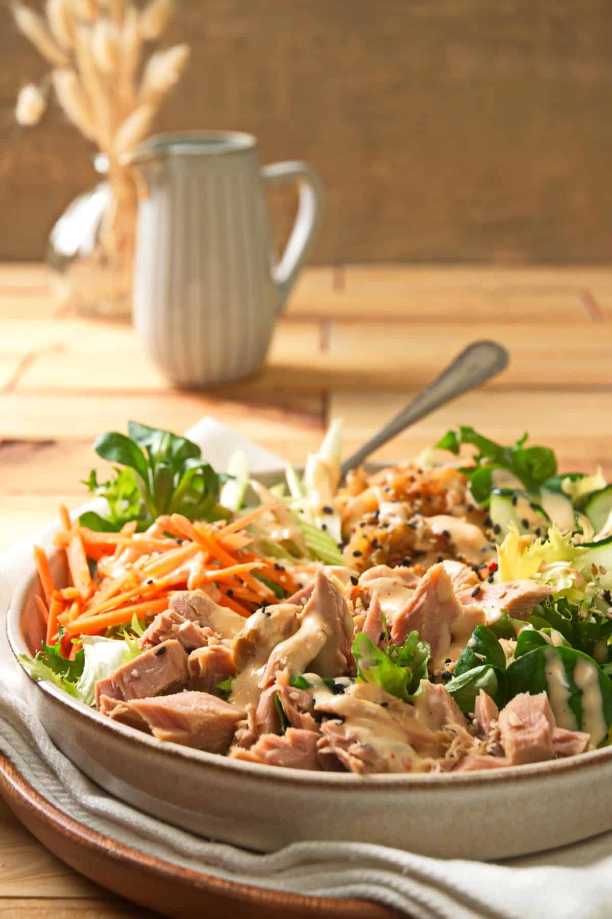 Kimchi tuna salad in bowl on wooden background with kimchi dressing.