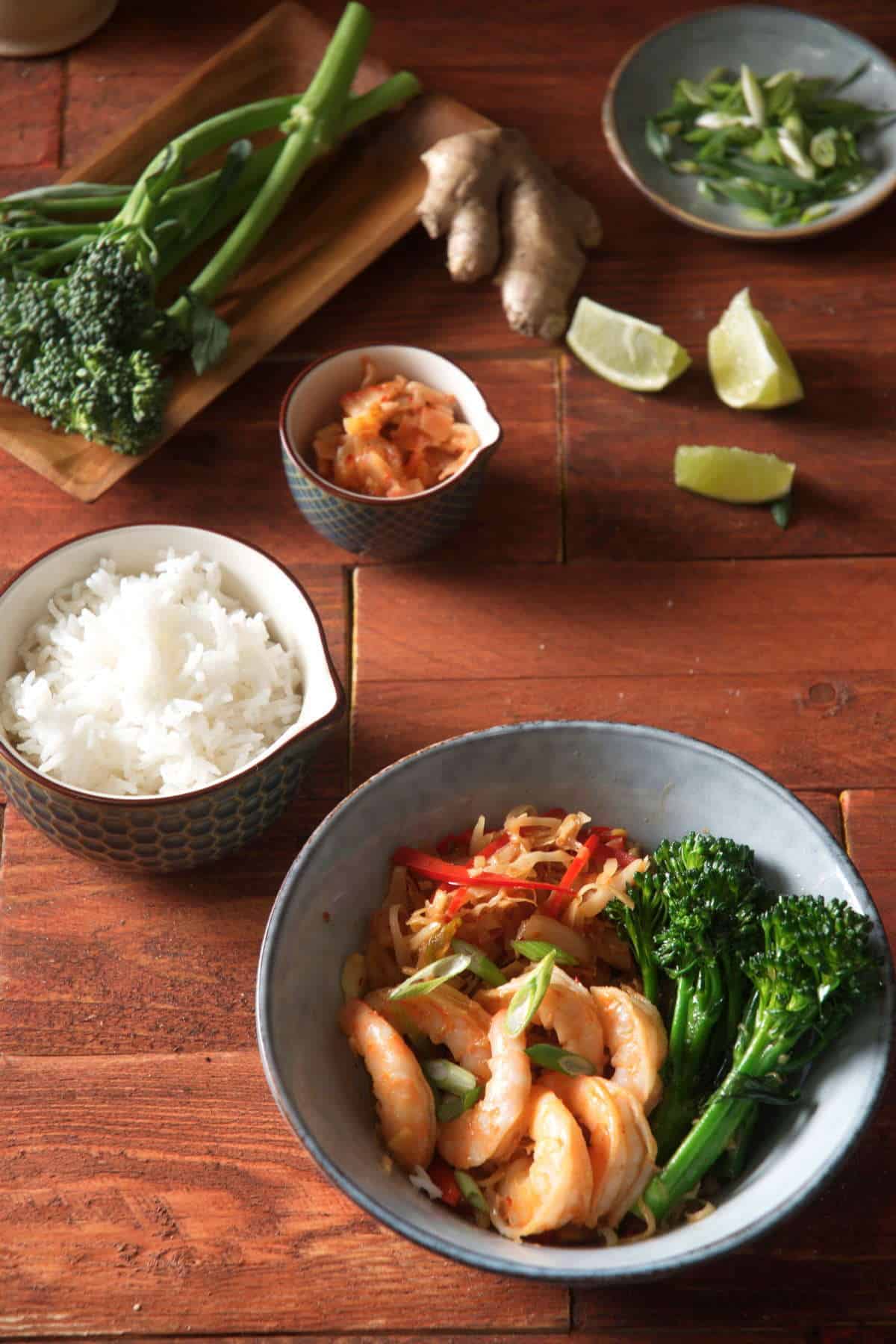 Kimchi shrimp stir fry over rice in a bowl on wooden background.