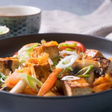Kimchi tofu stir fry on black dish.