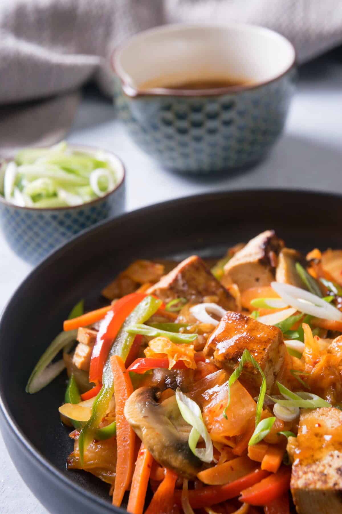 Kimchi tofu stir fry on black dish.