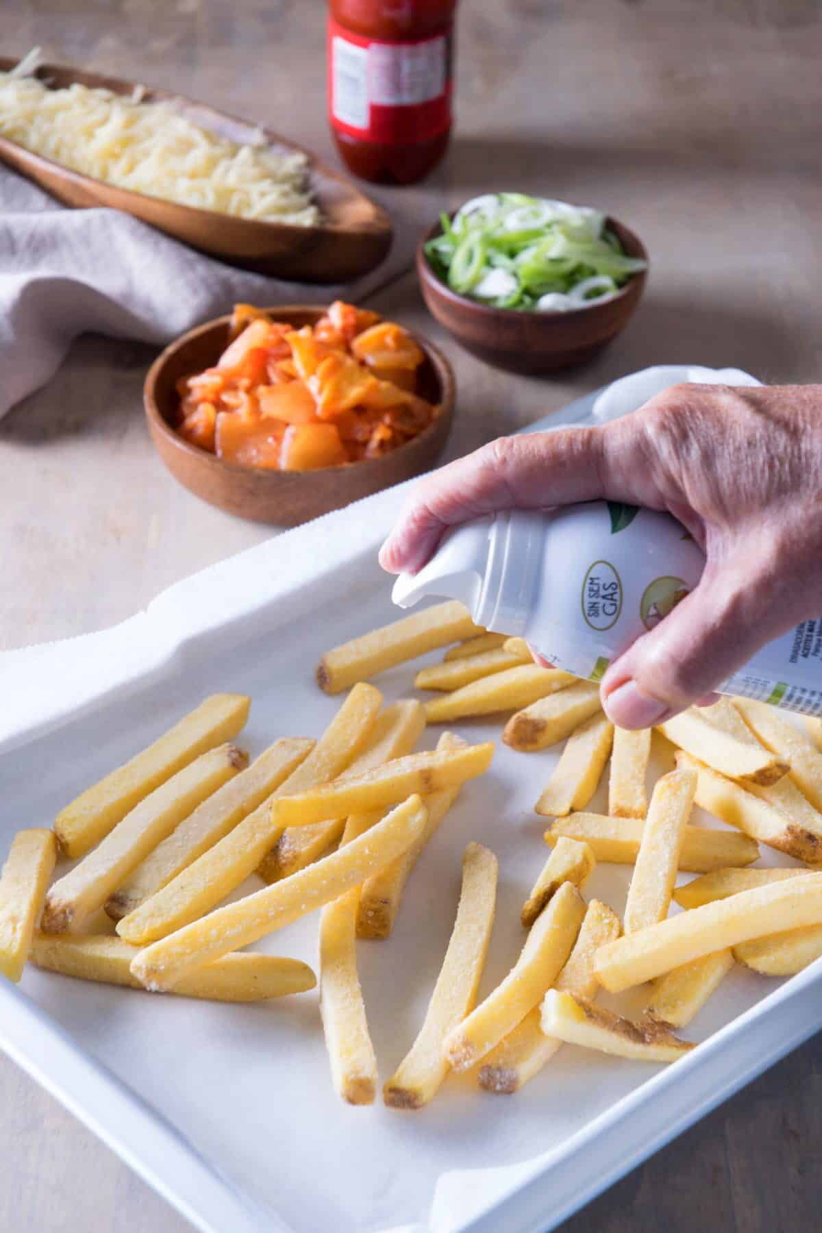 Frozen fries on baking sheet with olive oil cooking spray.