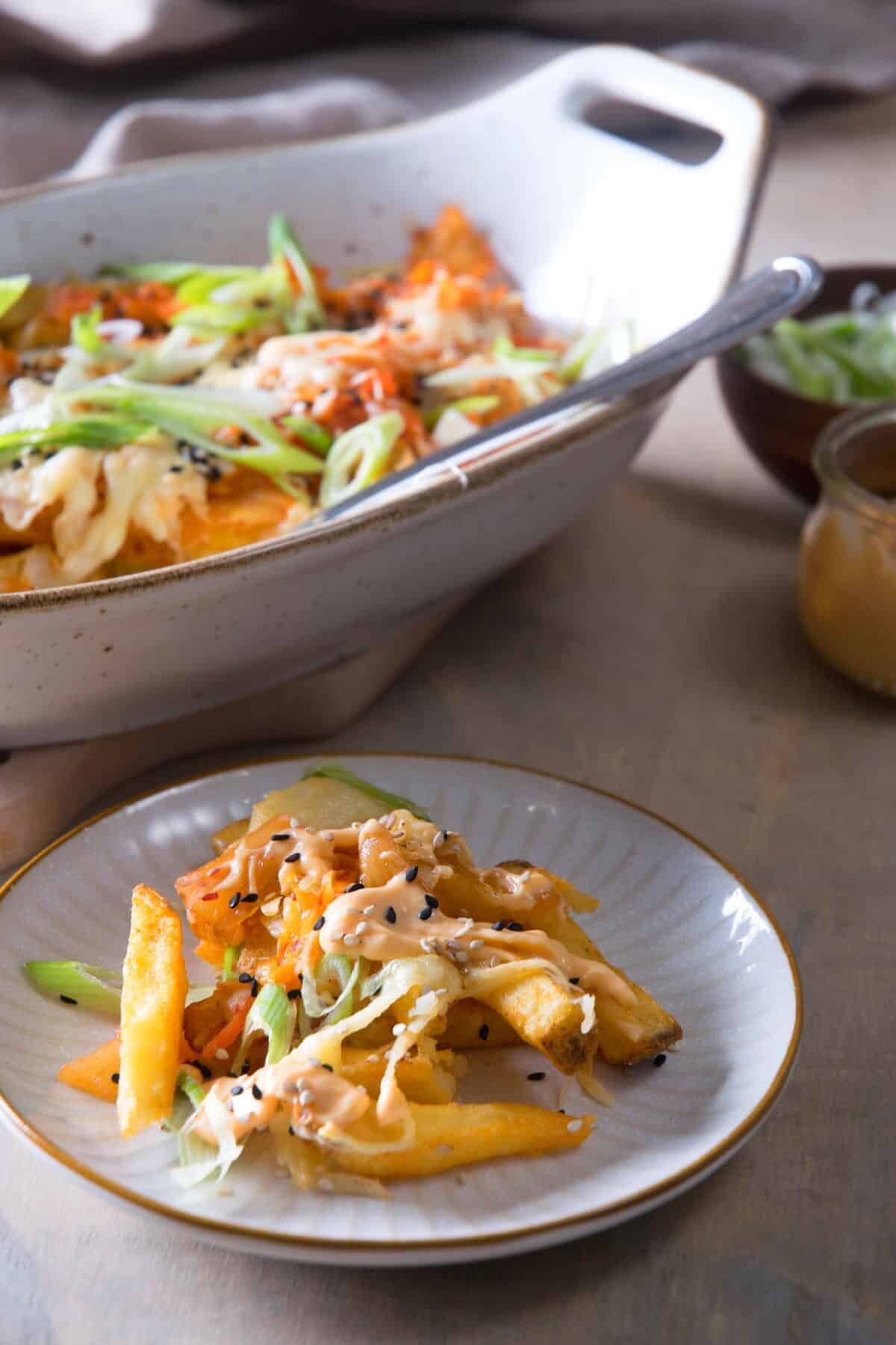 Fries with kimchi and cheese on a small plate. and in a casserole dish