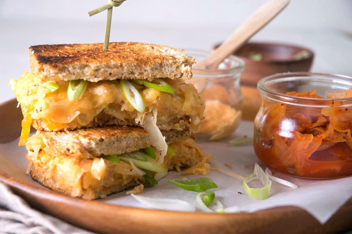 Kimchi grilled cheese sandwiches on a brown plate with kimchi on the side.