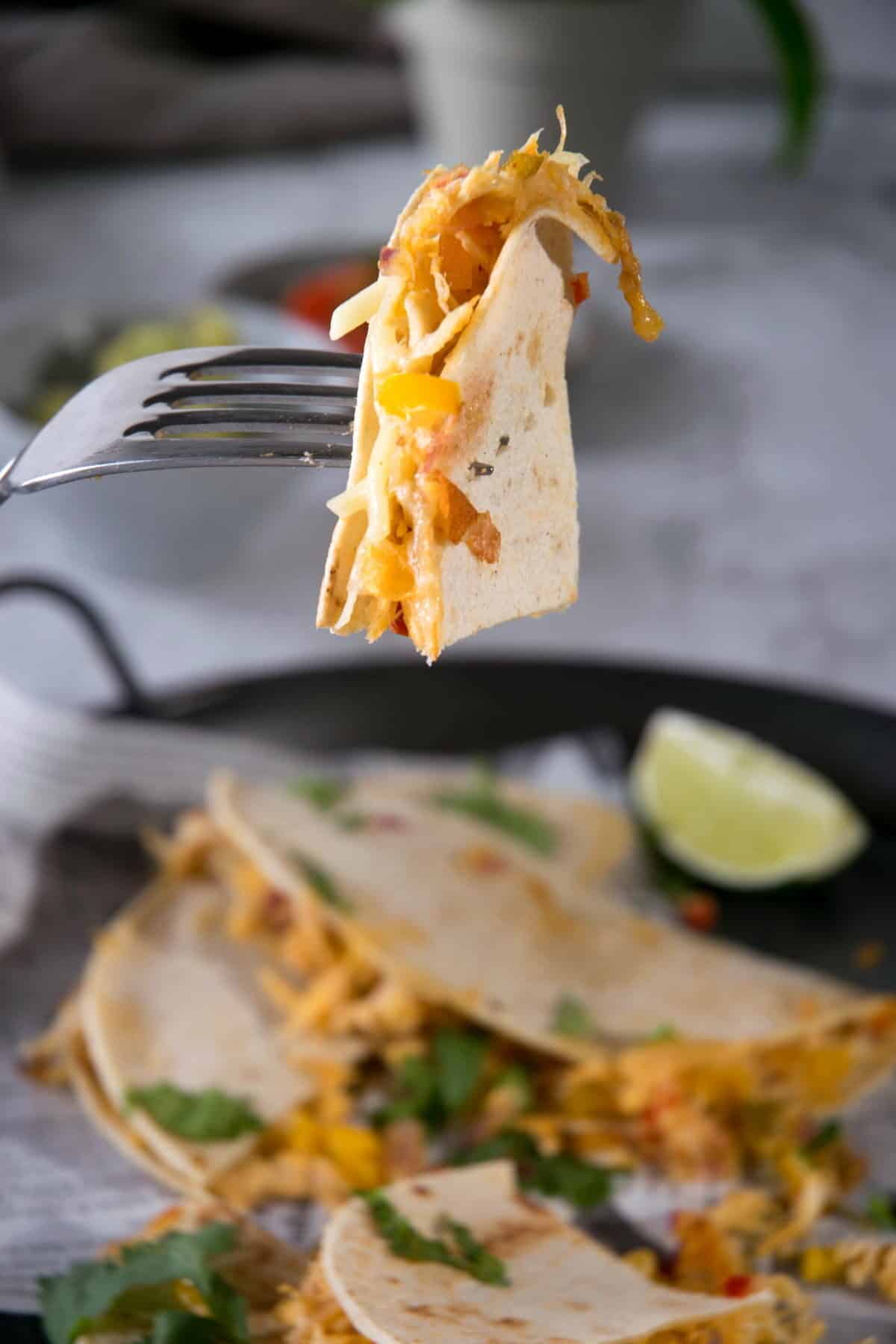 A fork with a piece of kimchi quesadilla.