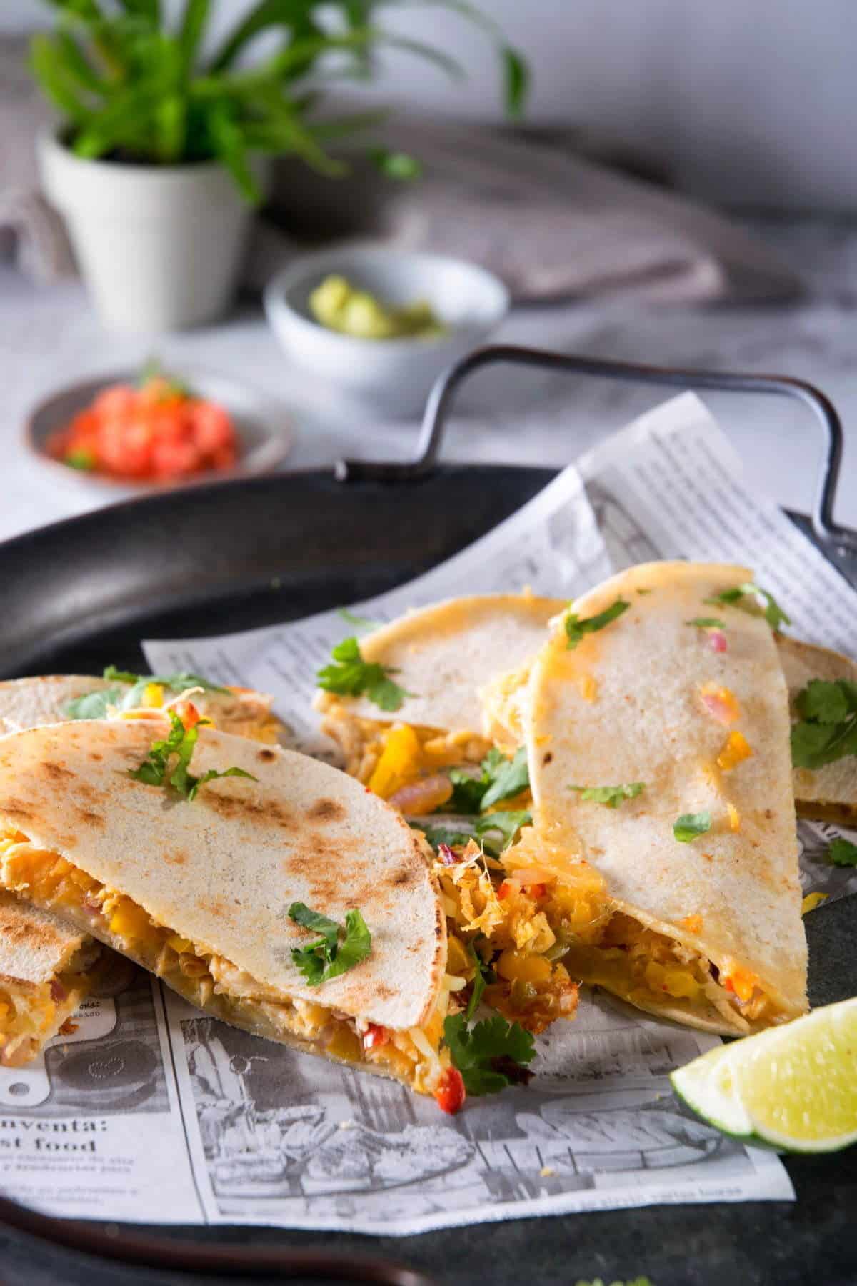 Kimchi quesadillas on dark plate and a lime wedge.