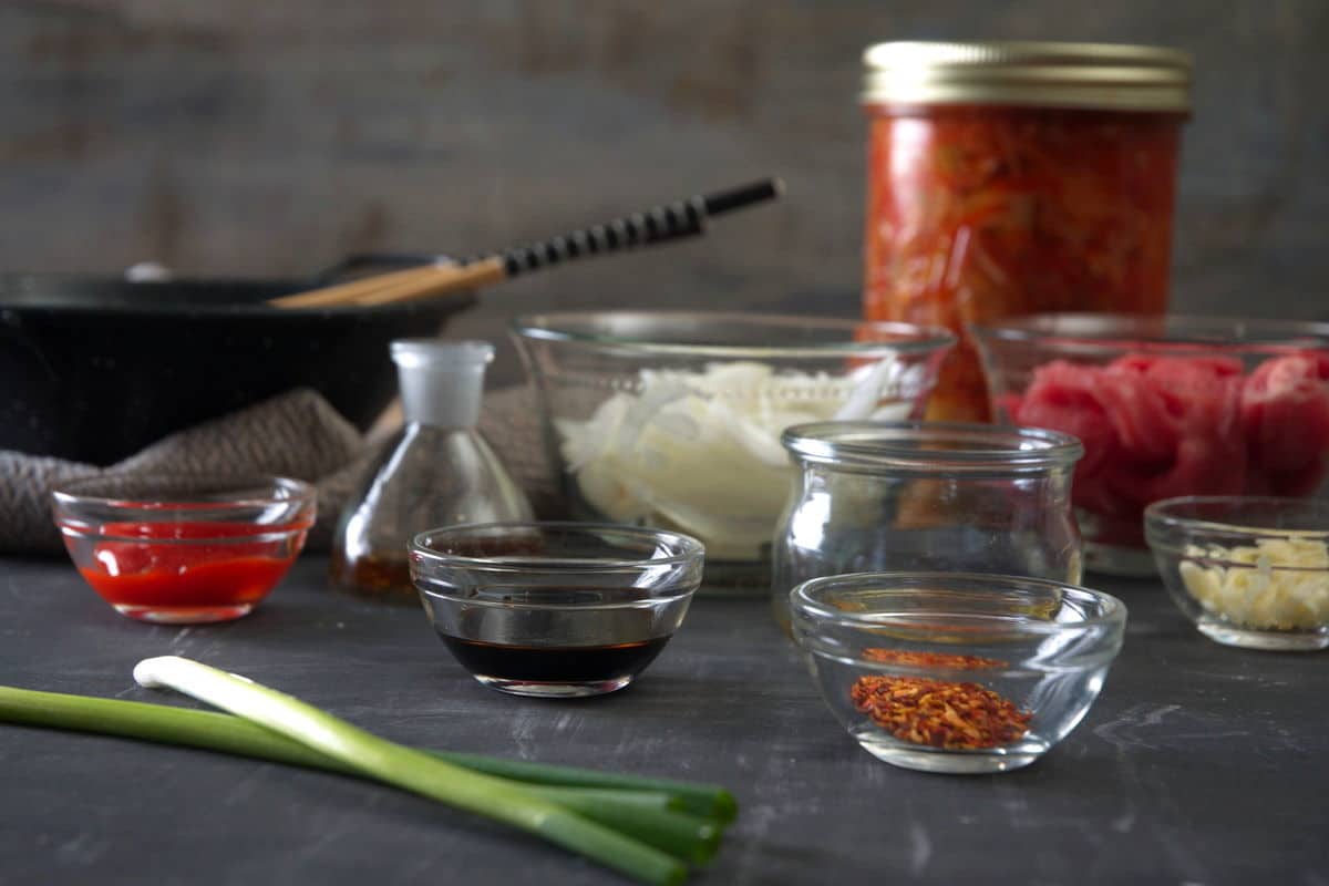 Kimchi stew ingredients prepped on dark background.
