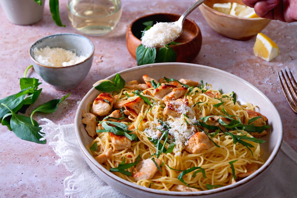 Front view of lemon basil pasta on white plate with Parmesan cheese on a spoon.