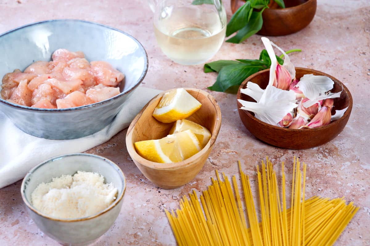 Lemon basil pasta ingredients prepped on marble background.